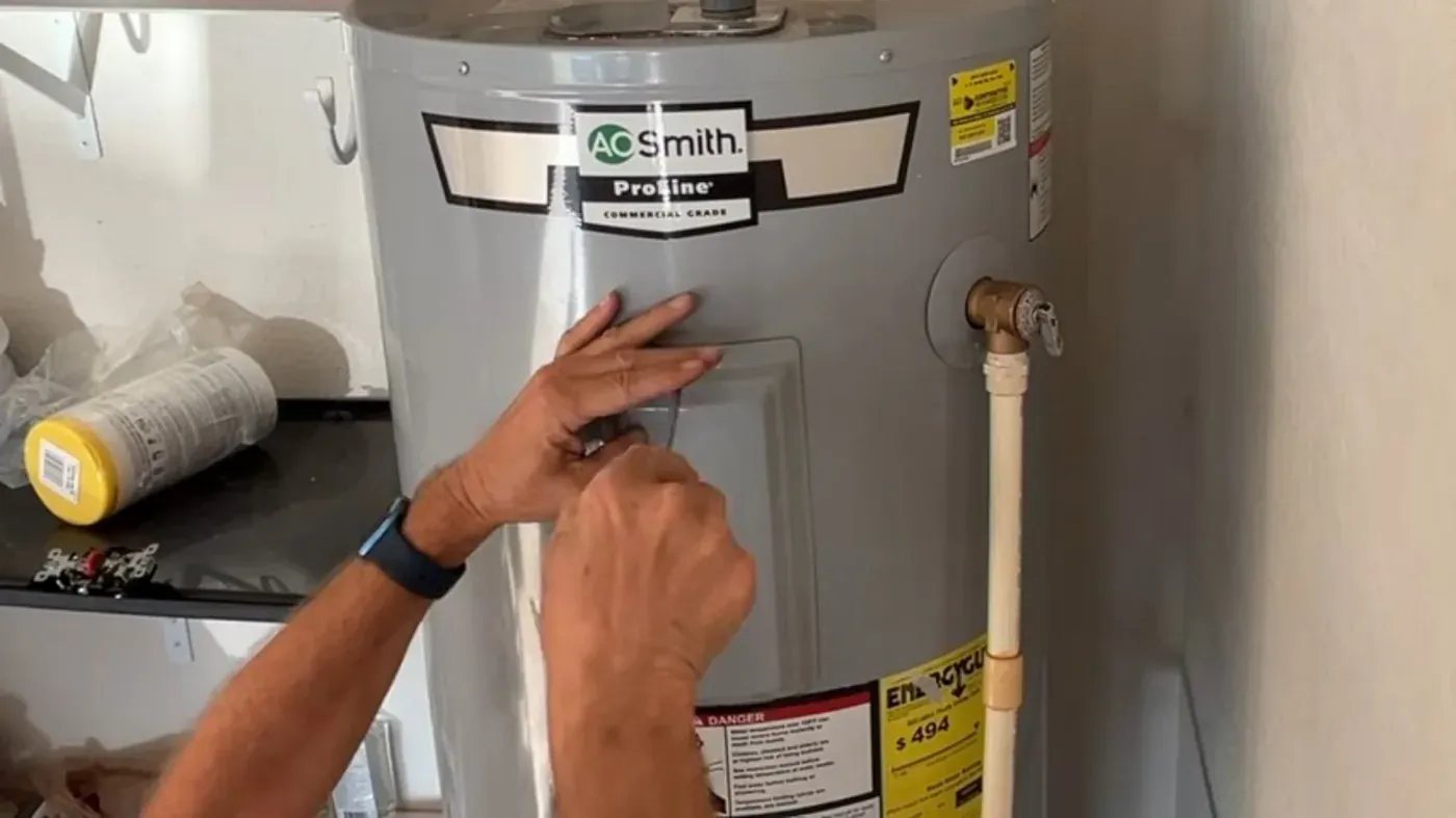 Hands removing the access cover on an electric storage tank, shown for electric unit repair in Littleton, CO